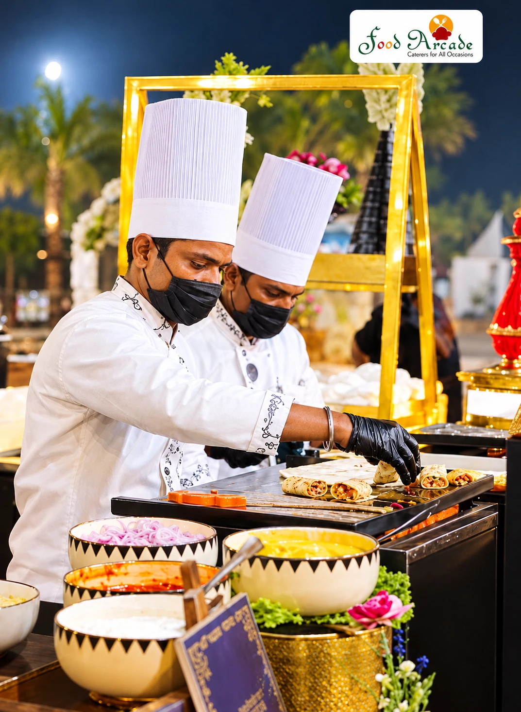 Two chefs in white rolling wraps on a griddle beside bowls of fillings under a night sky