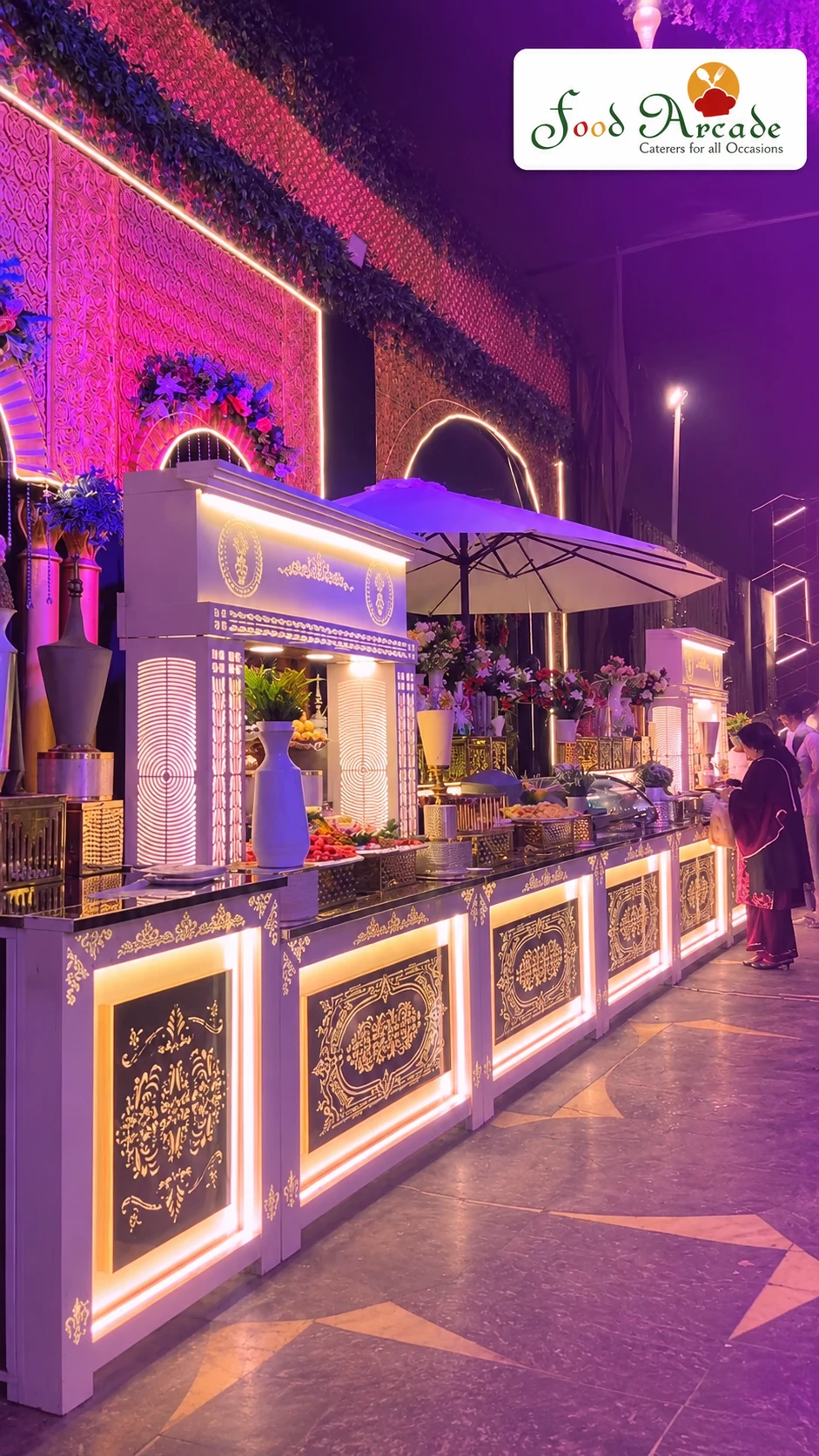 Long illuminated buffet counters with ornate panels under purple and pink evening lighting